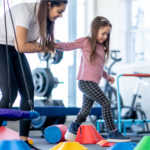 Therapist helping child through stepping stones in gym