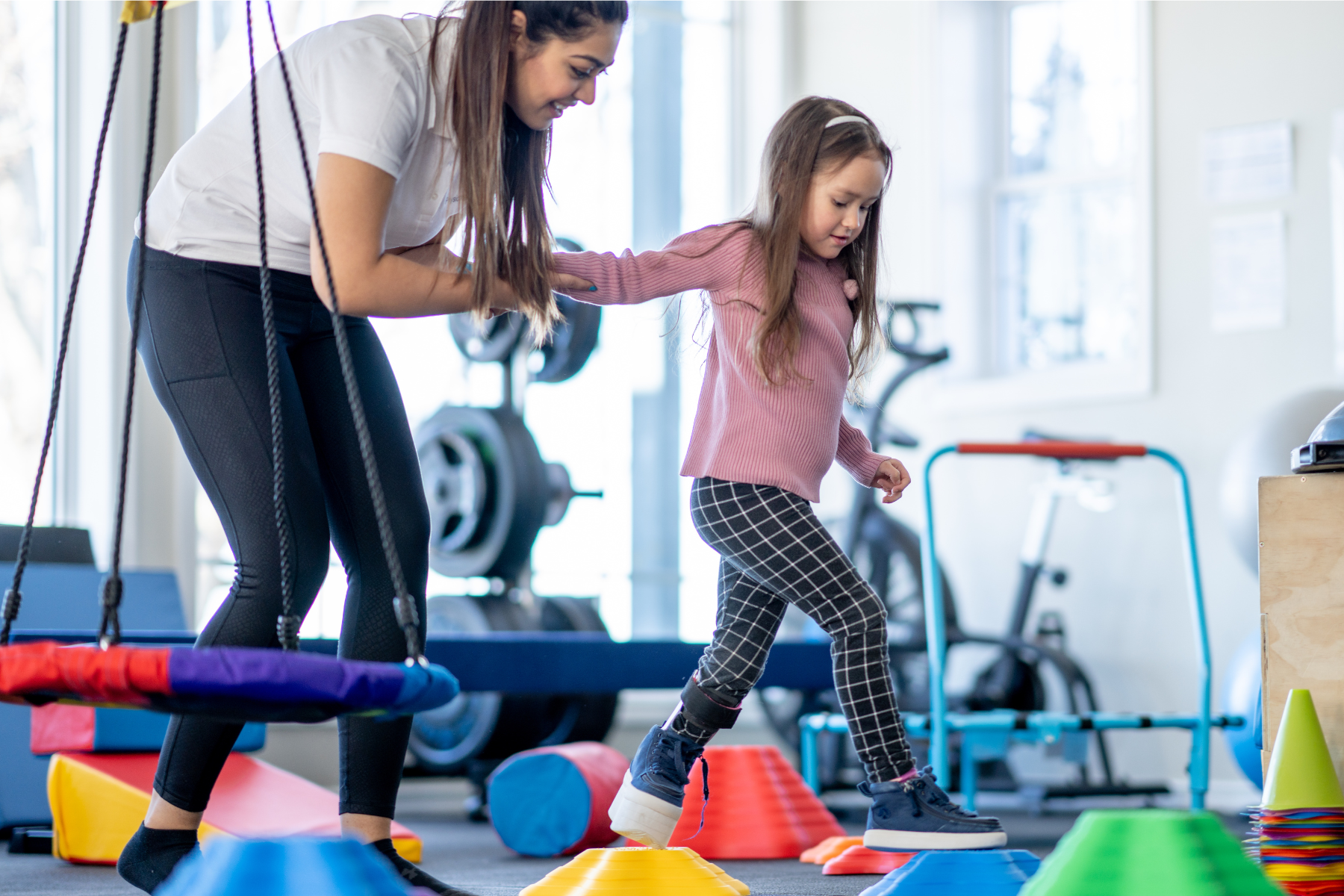 Therapist helping child through stepping stones in gym