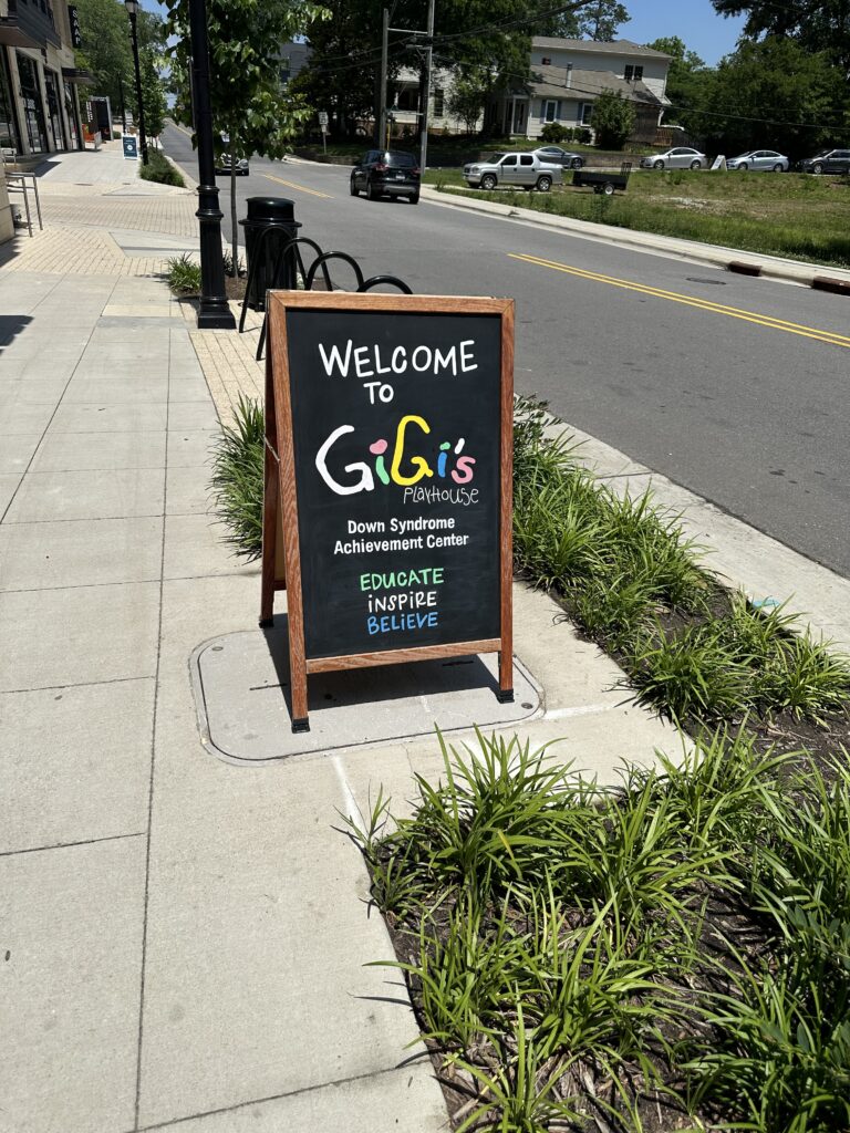 sign for Gigi's on sidewalk showing Cary Park in background